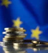 coins-on-table-against-european-union-flag-closeu-2026-03-27-01-23-08-utc